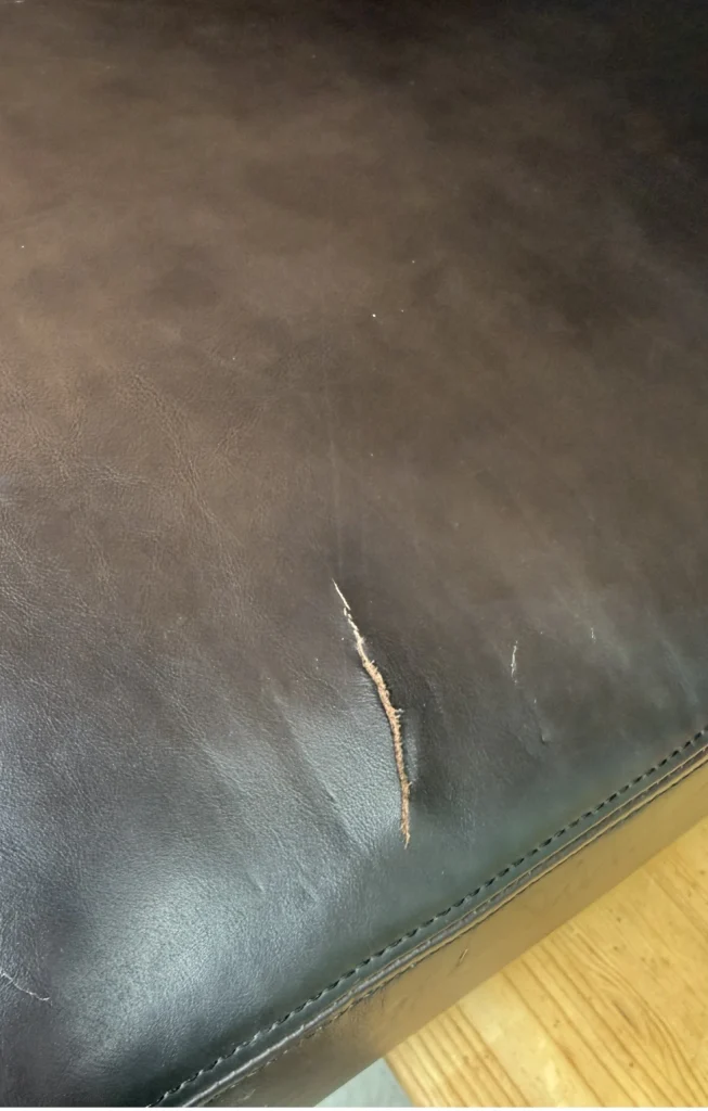 Damaged leather sofa with tear before repair in Charlotte NC