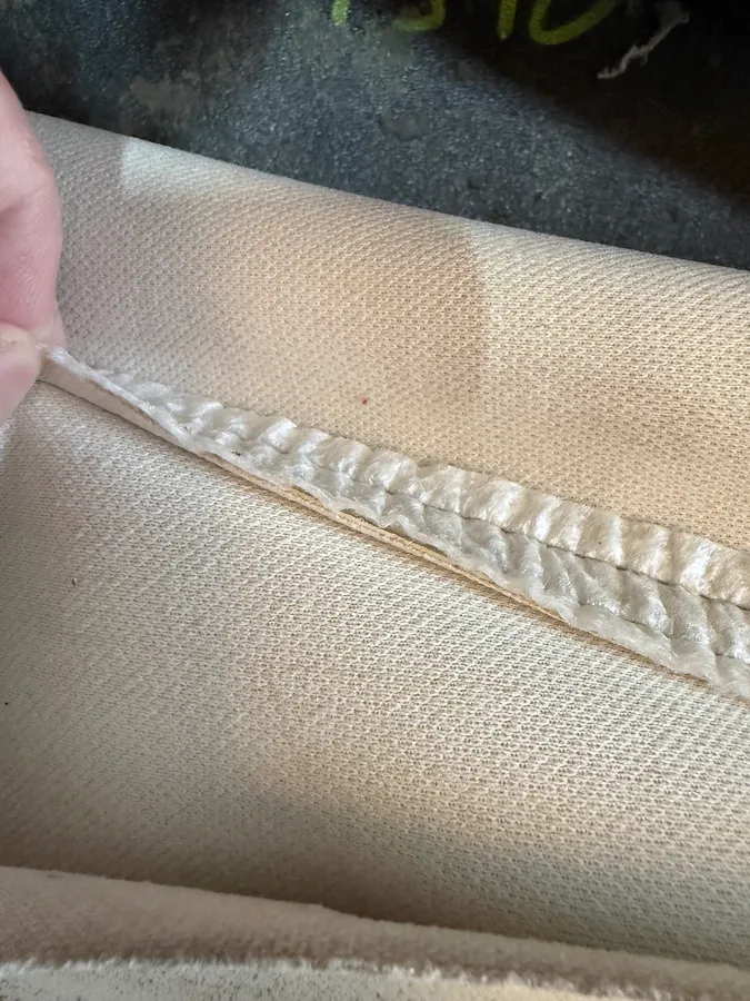 Close-up of a separated French seam on leather upholstery before professional restitching in Myers Park, Charlotte, NC